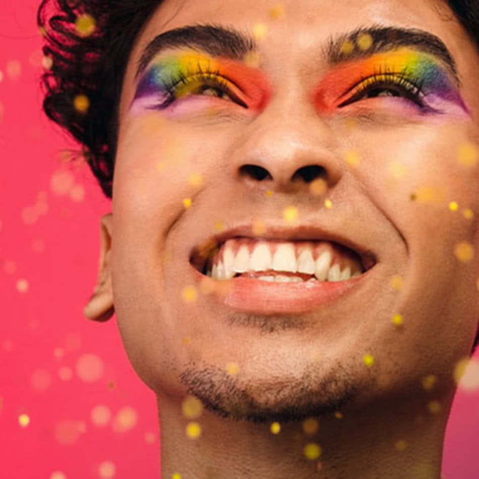 Close-up of smiling man with rainbow eye makeup